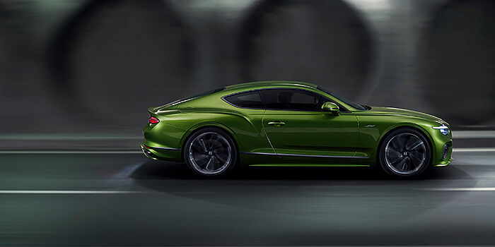 Bentley Ho Chi Minh Bentley Continental GT coupe in Tourmaline Green paint driving in profile on a dark road