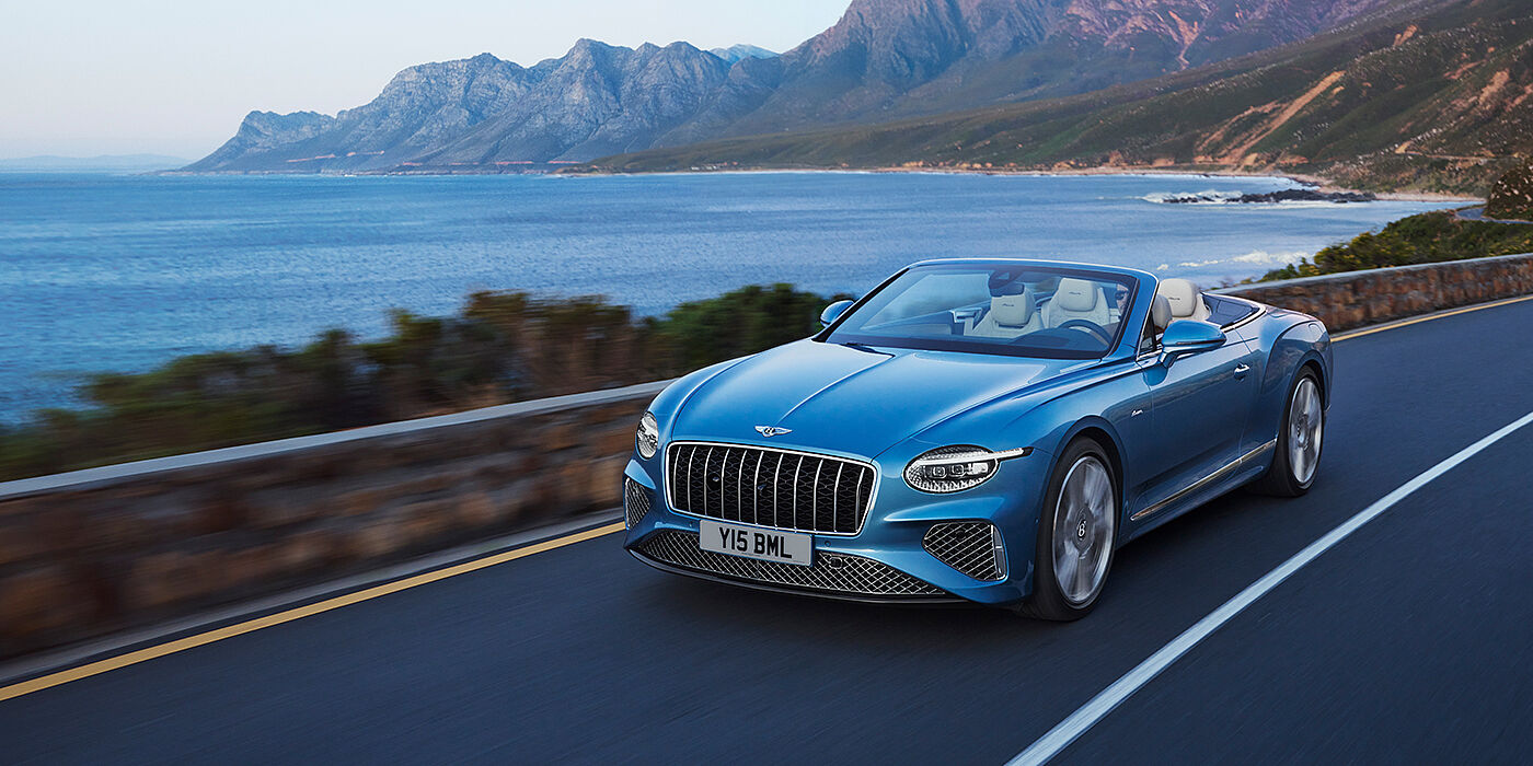 Bentley Ho Chi Minh New Bentley Continental GTC Azure convertible in Light Windsor blue paint with 22 inch Azure wheels and chrome grill, driving dynamically by the sea