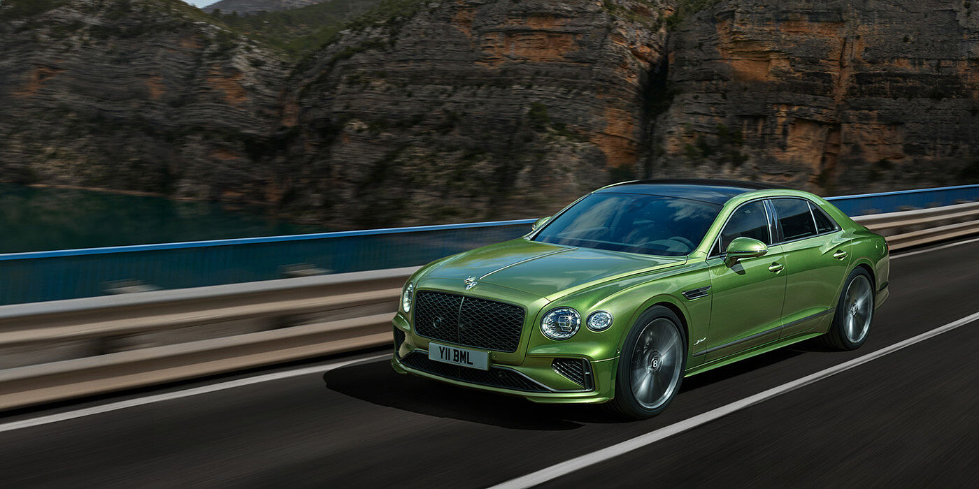 Bentley Ho Chi Minh Bentley New Flying Spur Speed v8 hybrid sedan driving dynamically on a mountain road in Tourmaline Green paint