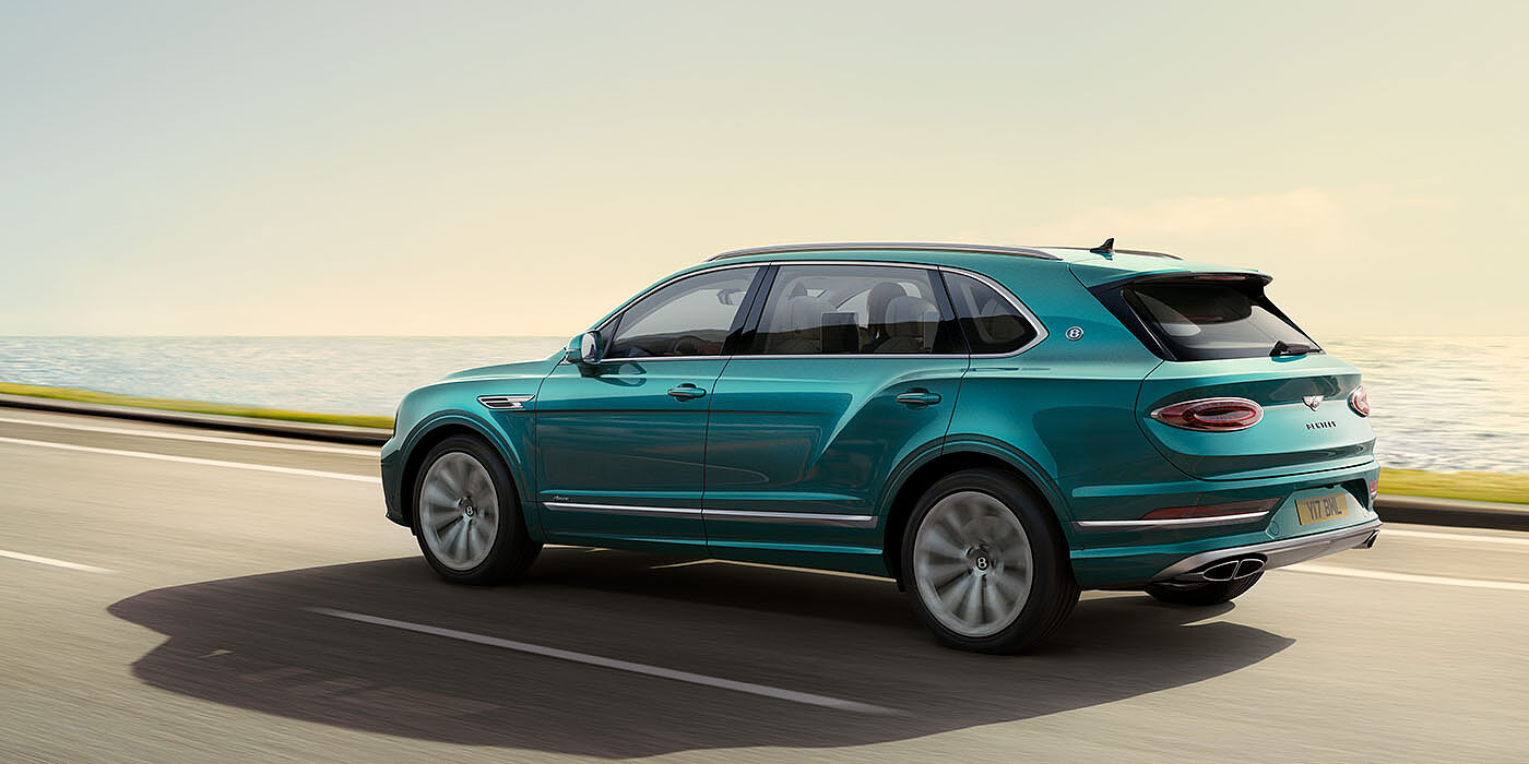 Bentley Ho Chi Minh Bentley Bentayga Extended Wheelbase Azure luxury SUV rear three quarter in Topaz Blue by Mulliner paint, driving on an ocean road.