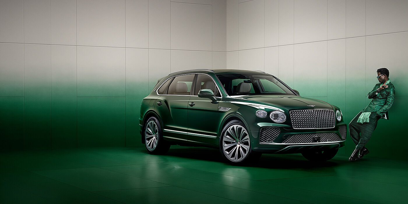Bentley Ho Chi Minh Wisdom K leans against wall next to Bentley Bentayga Extended Wheelbase Atelier Edition SUV in Light Emerald green paint