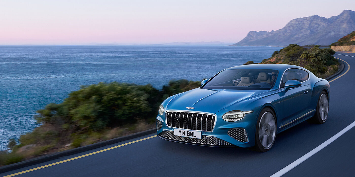 Bentley Ho Chi Minh New Bentley Continental GT Azure coupe in Light Windsor blue paint with 22 inch Azure wheels and chrome grill, driving dynamically by the sea