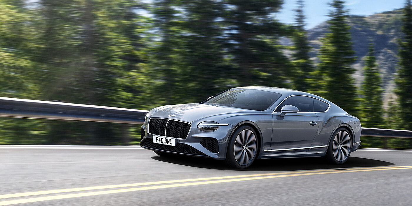 Bentley Ho Chi Minh New Bentley Continental GT coupe in Silverlake paint and 22 inch ten-spoke wheels, driving dynamically on a tree-lined road in the sunshine