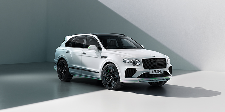 Bentley Bentayga Speed SUV in 3/4 view in Glacier White exterior with striking Hyper Green accents on the front bumper, wheel rims, and mirror caps – embodying a bold, high-performance presence with a sporting edge